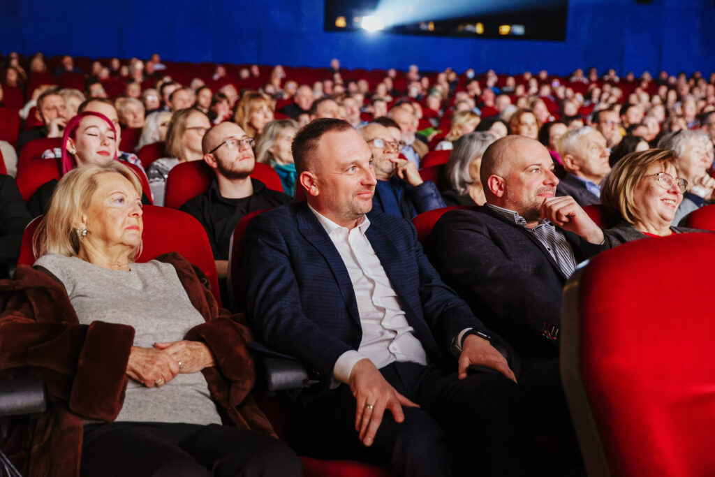 Zdjęcie sali kinowej wypełnionej gośćmi. Wszyscy patrzą na ekran poza kadrem.