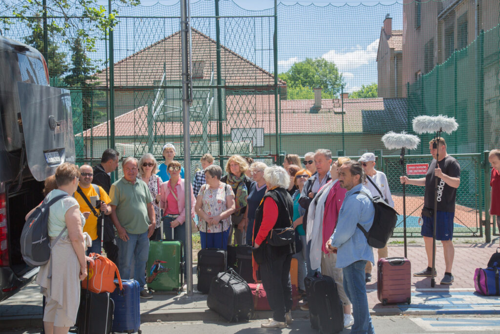 Grupa aktorów ITANa z walizkami i plecakami stojąca przed busem. Zbiórka przed wyjazdem.
